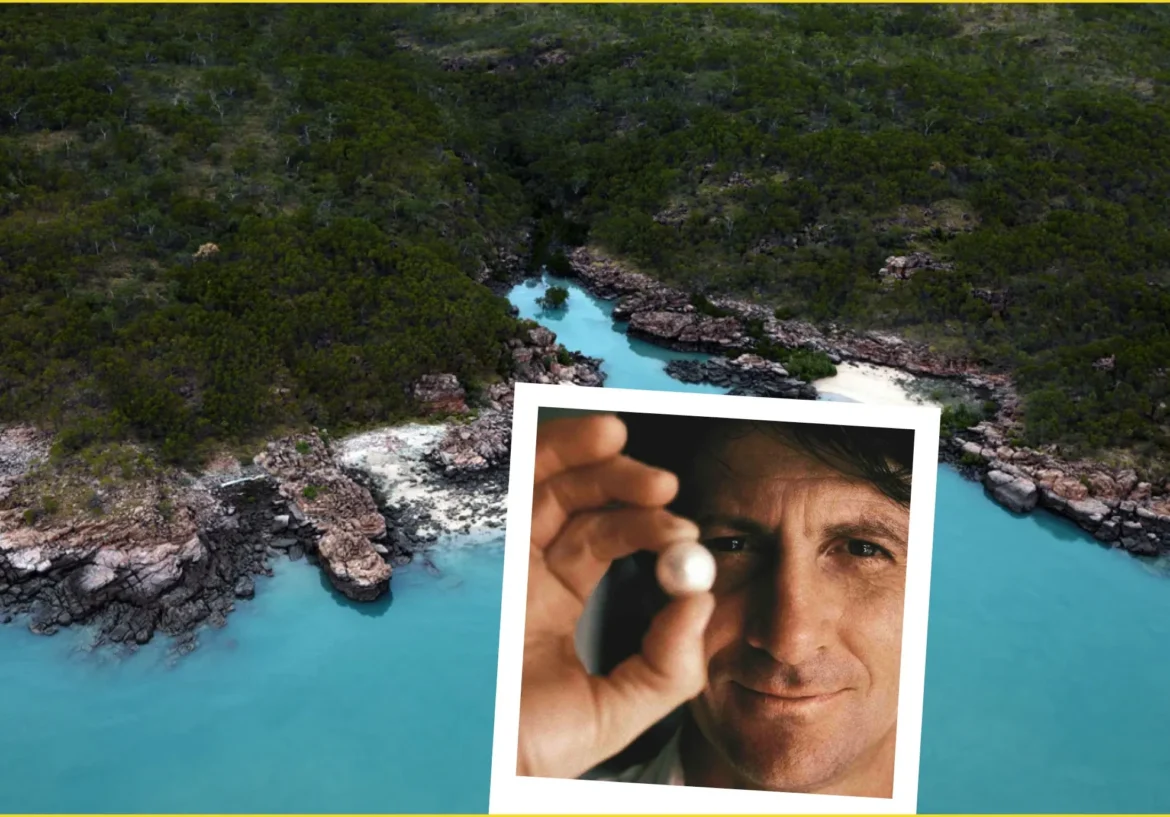 Aerial view of turquoise water and rocky coastline with green forest, overlaid by a photo of a man holding a pearl near the camera.