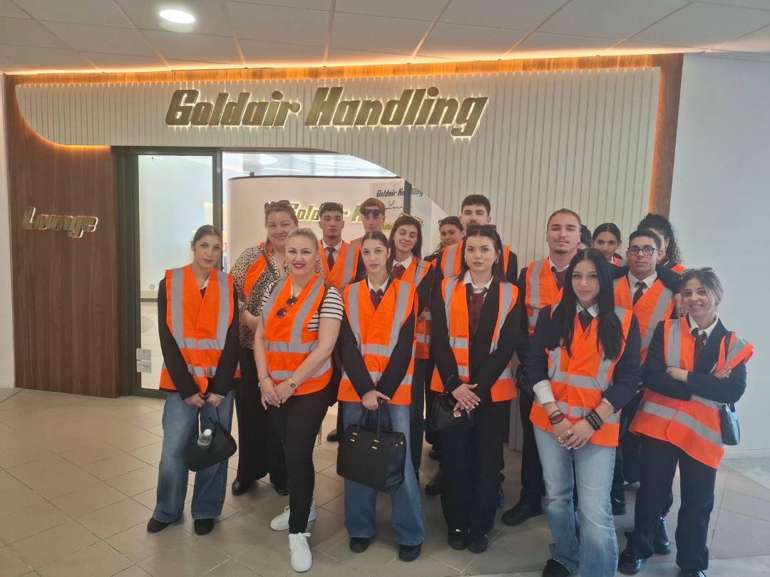 Group of staff in orange safety vests posing for a team photo inside the Goldair Handling lobby.