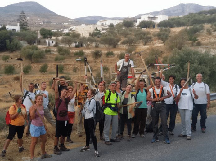 Group of volunteers posing with ladders and tools on a rural hillside during a community workday.