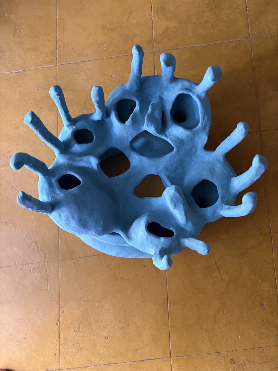 Blue 3D sculpted model with hollow holes and spike-like protrusions, resembling a virus for educational display.