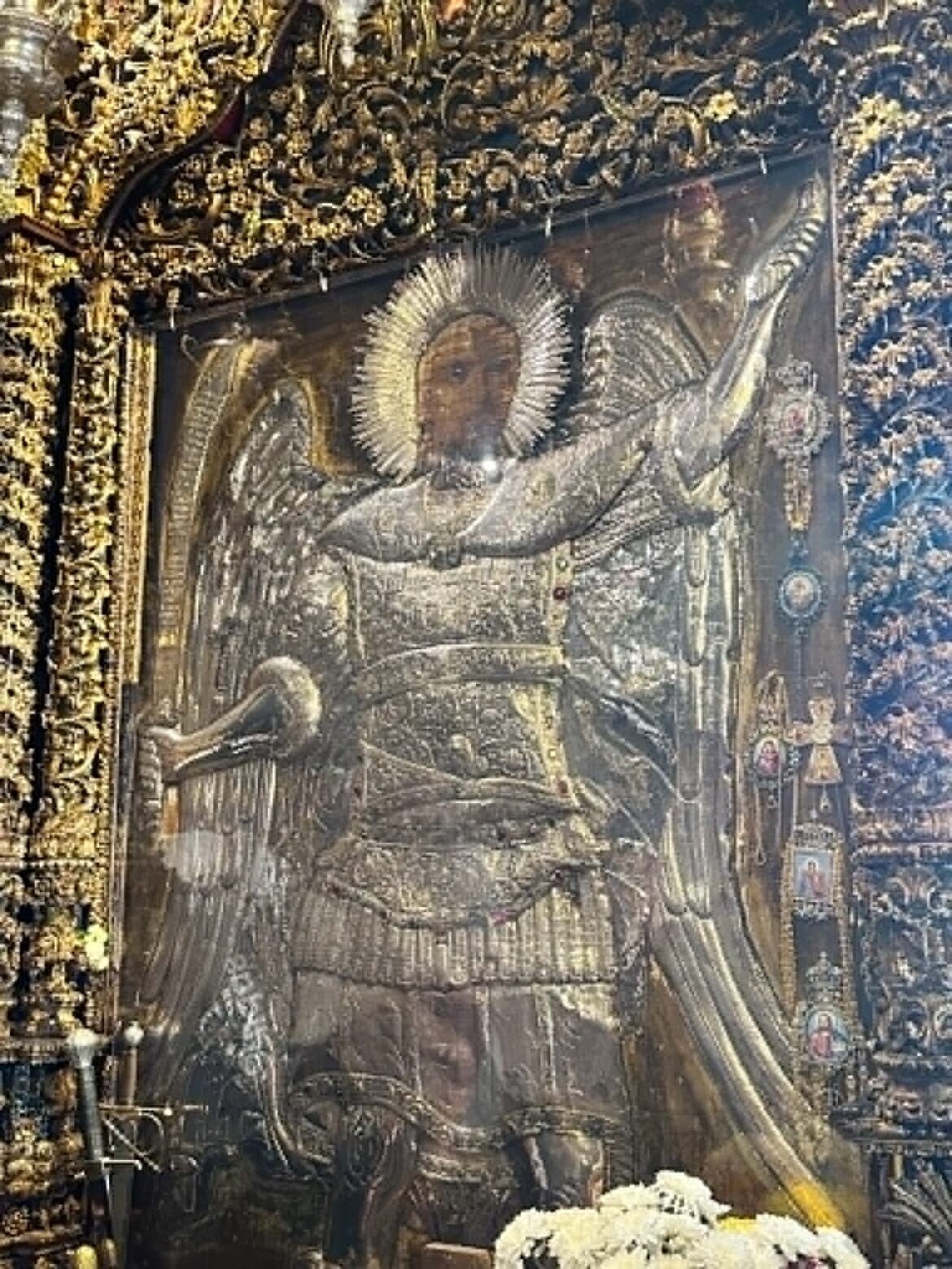 Ornate gold frame around a damaged religious icon with a halo, surrounded by grime and rubble.